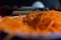 Pile of grated carrot on white plate with blurry background