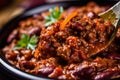 Extreme close-up of a spoonful of homemade chili con carne with fresh herbs and spices on top