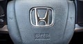 Close-up shot of a Honda Logo with SRS AirBag and horn icons on a car steering wheel..