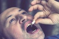 Extreme closeup man face taking white pill, mouth view swallowing pills, illness. man take medicine,open mouth and bring