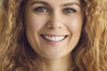Extreme closeup portrait of a happy woman with wavy hair and a friendly white smile