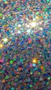 Macro view of a vibrant and sparkling glitter texture with a array of multicolored hexagonal and round particles reflecting light Royalty Free Stock Photo