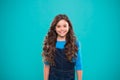 Extreme hair volume. Kid girl long healthy shiny hair. Kid happy cute face with adorable curly hairstyle stand over blue Royalty Free Stock Photo