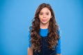 Extreme hair volume. Kid girl long healthy shiny hair. Kid happy cute face with adorable curly hairstyle stand over blue Royalty Free Stock Photo