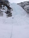 Male mountain ice climber climbing a steep and long frozen waterfall in the Swiss Alps in deep winter