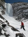 Male mountain ice climber rapelling off a steep and long frozen waterfall in the Swiss Alps in deep winter