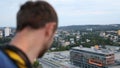 Extreme male roofer looking down from top of skyscraper, adrenaline addict