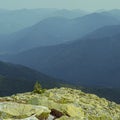 Extreme hikes. Huge stones overgrown with green ome stoch against the backdrop of high mountain ranges in the fog