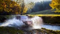 Extreme offroad car through river water generating splashes and sparks in the Carpahtians Mountains at sunset with beautiful