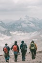 Extreme recreation and mountain tourism. A group of four tourists walking on a mountain trail. In the background, large snow-