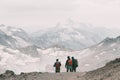 Extreme recreation and mountain tourism. A group of hikers down the mountain path over the horizon. In the background, large snow-