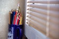 Extreme shallow of depth. Bunch of colorful pencils kept in a cup next to window light against white designer wallpaper Royalty Free Stock Photo