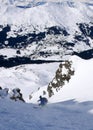 Extreme skier skiing down a narrow snow couloir with a view of alpine villages far in the valley below in Switzerland