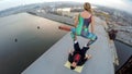 Extreme sport, female balancing on male legs on top of bridge, dangerous hobby