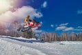 Sports race snowmobiles. Snowmobile in high jump above track. Sportsman on snowmobile. Winter competition, sunny day, Copy space.