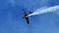 Extreme stunt plane with black wings flying in the blue sky with white smoke