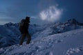 Extreme tourism. Brave expeditor lights the way with a headlamp at night winter mountains. Man with backpack commit climb on snowy Royalty Free Stock Photo