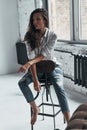 Extremely beautiful. Attractive young woman in casual wear looking away while sitting on the chair at home Royalty Free Stock Photo