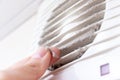 Extremely dirty and dusty white plastic ventilation air grille at home close up and a hand holding dust by fingers, harmful for