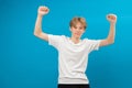 Extremely excited teen boy shouting making yes gesture, amazed with his victory, triumph. Indoor studio shot isolated on blue