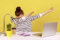 Extremely excited woman office worker sitting at workplace with laptop, showing dab dance gesture.