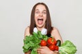 Extremely happy adult woman with brown hair standing isolated over white background holding vegetables screaming with excitement Royalty Free Stock Photo