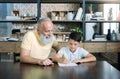 Extremely happy elderly man looking at grandchild doing his homework Royalty Free Stock Photo