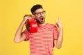 Extremely happy joyful man with beard in eyeglasses and red striped t-shirt holding tape recorder on shoulder and showing rock and Royalty Free Stock Photo