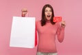 Extremely happy surprised woman holding in hands paper shopping bags and sale card, looking at cameras with big eyes and opened Royalty Free Stock Photo