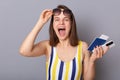 Extremely happy woman tourist holding cellphone and passport wearing striped swimming suit, raised her sunglasses, yelling with Royalty Free Stock Photo