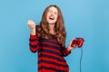 Woman yelling happily, celebrating completing level in video games, holding red joypad.