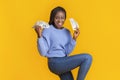 Extremely happy young black woman holding money in both hands