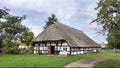Extremely large half-timbered house with huge broad bluegrass. Mighty hut with a thatched roof against a cloudy gray sky. East