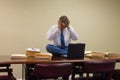 Extremely stressed out upset overworked man at work sitting on table with stacks of project folders Royalty Free Stock Photo