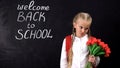 Extremely upset girl with tulips standing near chalkboard, not wanting to school Royalty Free Stock Photo