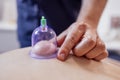 Extrime close up of of the male hand of the masseur putting vacuum healing can on the back of his client