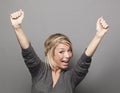 Extrovert 20s blonde woman raising hands for victory