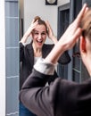 Extrovert young beautiful business woman enjoying looking at home mirror