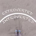 Extroverted vs Introverted text on asphalt ground, feet and shoe Royalty Free Stock Photo