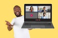 An exuberant man joyously gestures towards a laptop displaying a video conference