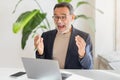 An exuberant middle-aged businessman with glasses joyfully reacts during a video call