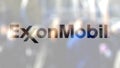 ExxonMobil logo on a glass against blurred crowd on the steet. Editorial 3D rendering