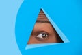 Eye of african-american man peeking throught triangle in blue background Royalty Free Stock Photo