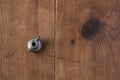 Eye bolt for attaching a handle from an old aluminum home manual meat grinder on a wooden table.