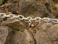 Eye bolt with iron chain anchored into sandstone rock. Twisted chain Royalty Free Stock Photo