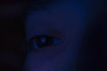 Eye in the dark close-up. Young boy looks at social networks. There is a Facebook symbol in the eye during the quarantine. Royalty Free Stock Photo