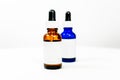 Eye dropper bottles with blank white label, in brown and blue, depicting medicine, formula or administration of a liquid drug or Royalty Free Stock Photo