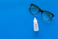 Eye drops in small bottle near glasses on blue background top view copy space Royalty Free Stock Photo