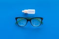 Eye drops in small bottle near glasses on blue background top view copy space Royalty Free Stock Photo