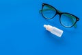 Eye drops in small bottle near glasses on blue background top view copy space Royalty Free Stock Photo